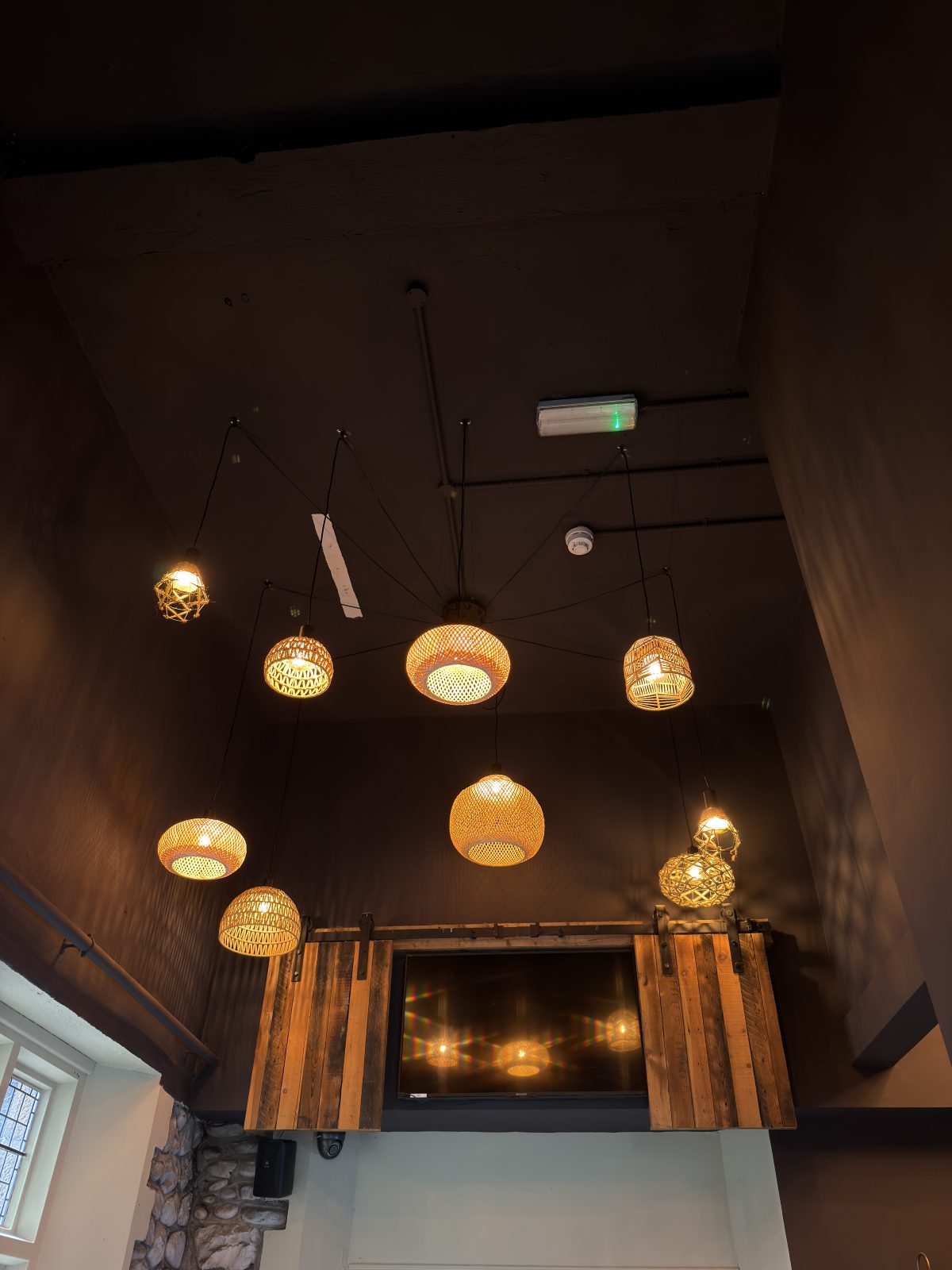 Cluster of woven rattan pendant lights installed above a bar in Cardiff